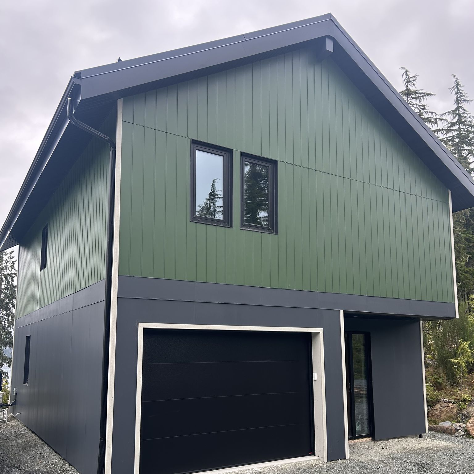 A completed Stackbl home: two storeys with green vertical siding over a charcoal garage level