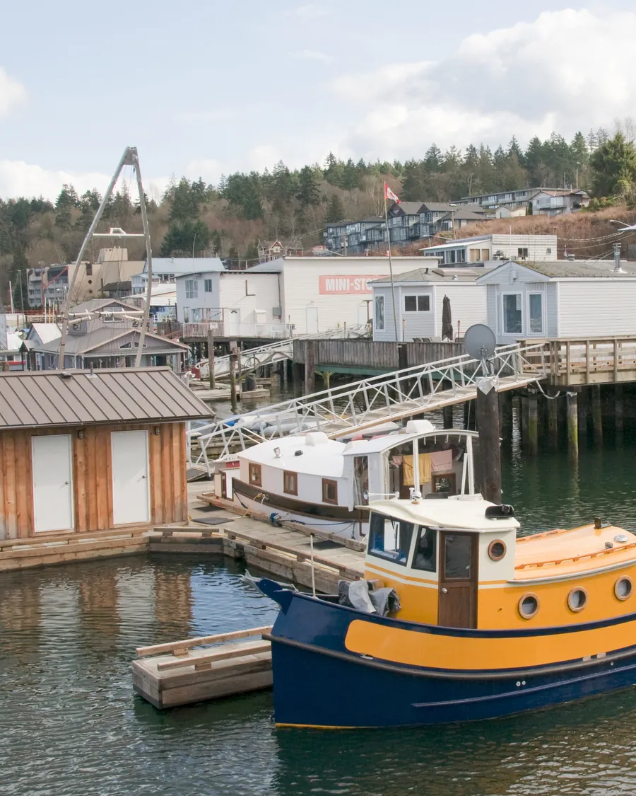 Cowichan Bay waterfront with floating homes, a wooden pier and a yellow tugboat